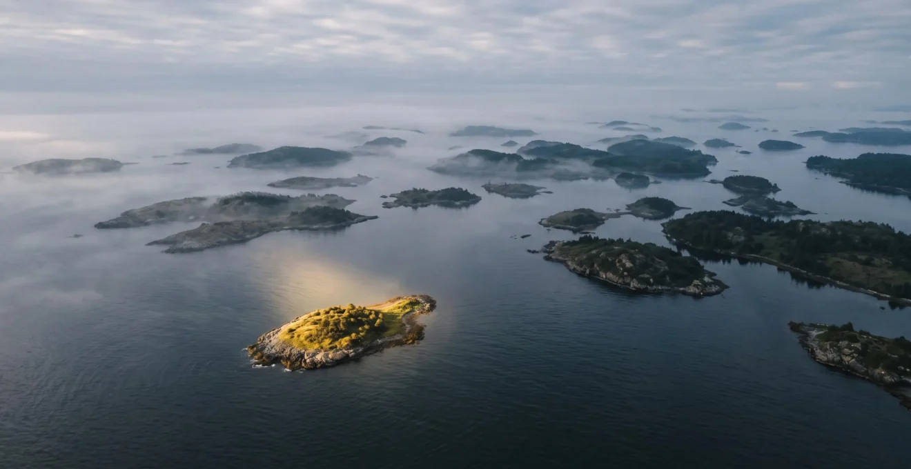 Vue aérienne symbolique d'un phare éclairant une petite île isolée au milieu d'un vaste archipel, représentant l'identification d'une niche médiatique à fort potentiel